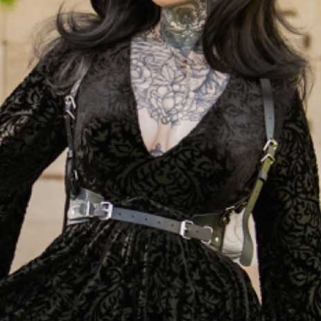 Person wearing a black lace dress with a white patterned bag.