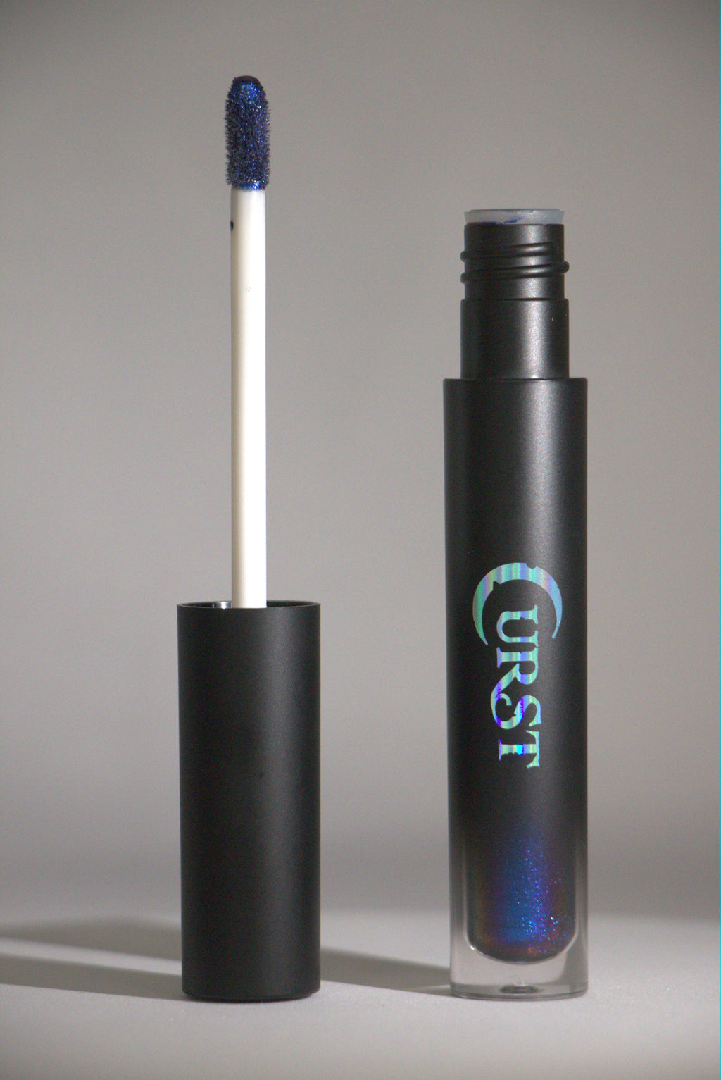 Black lip gloss tube with blue glittery applicator on a gray background
