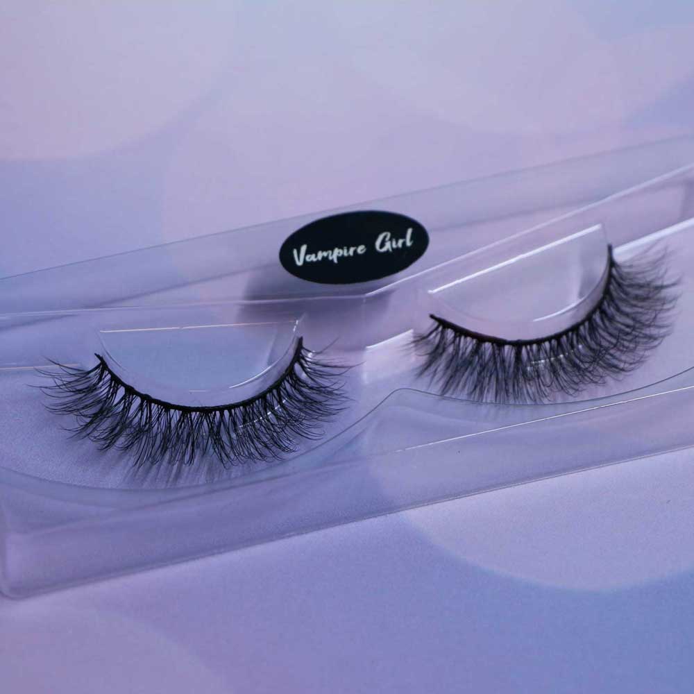Pair of false eyelashes in a clear case with 'Vampire Girl' branding on a light purple background.