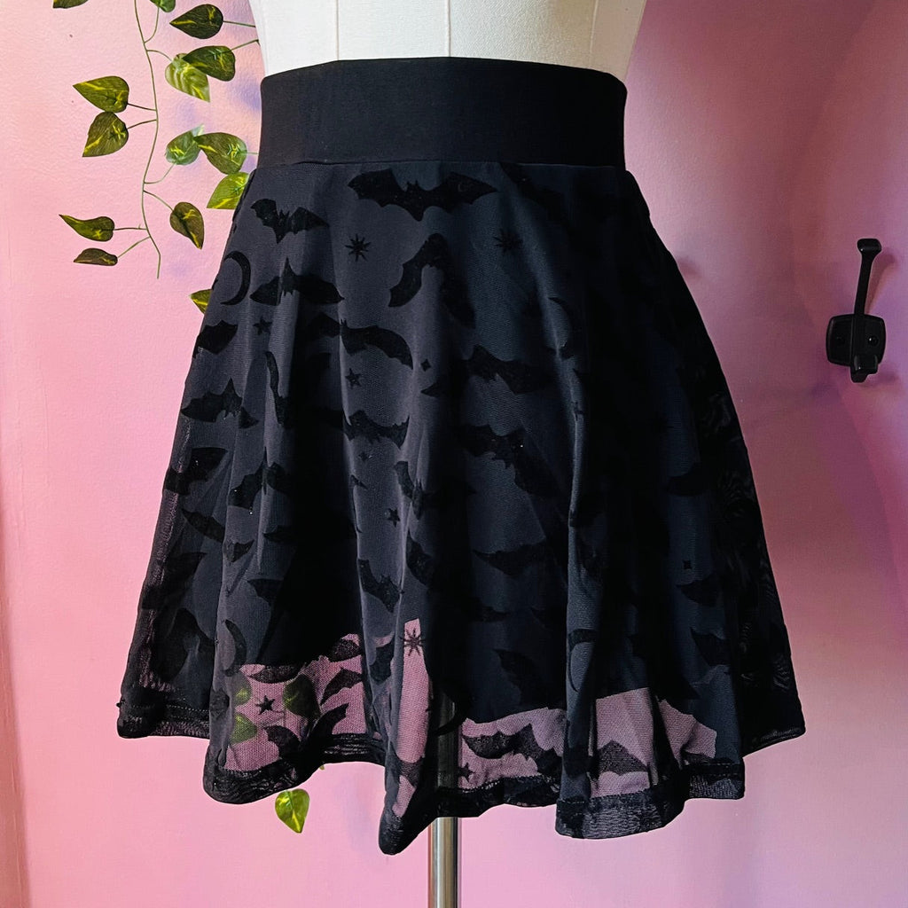 Black skirt with bat pattern on a mannequin against a pink background