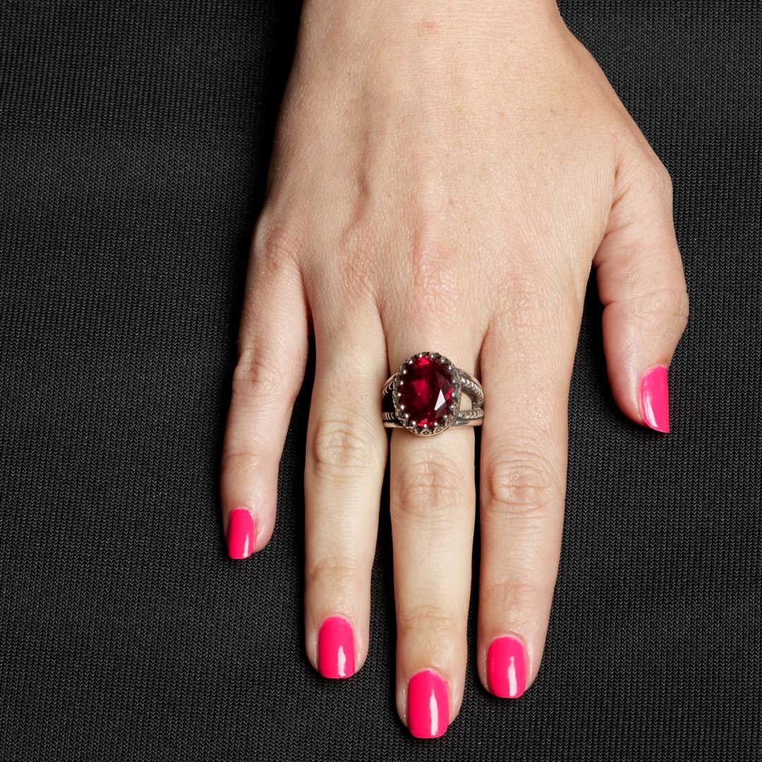 Hand wearing a ring with a red gemstone on a black background
