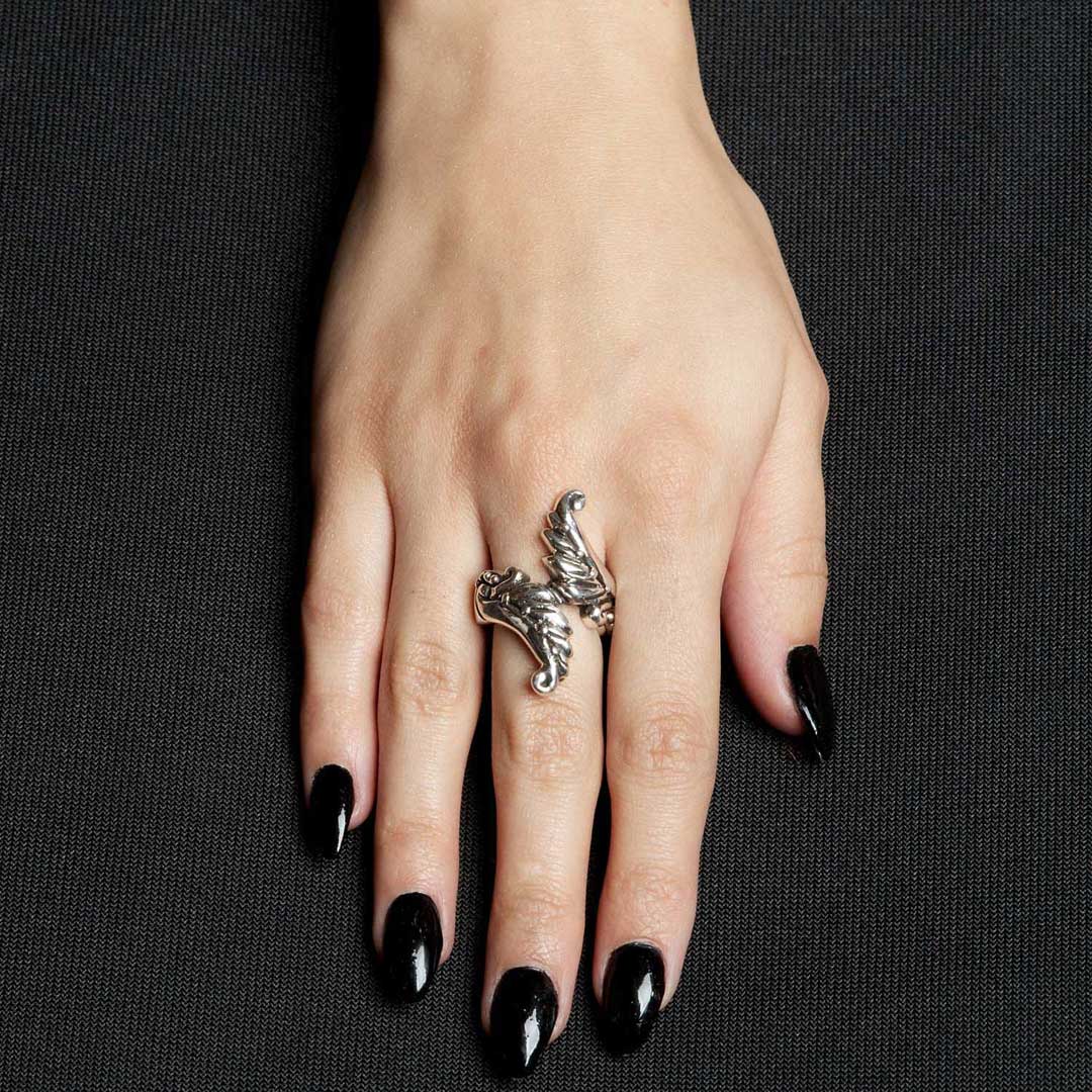 Hand wearing a silver ring with black nail polish on a dark background