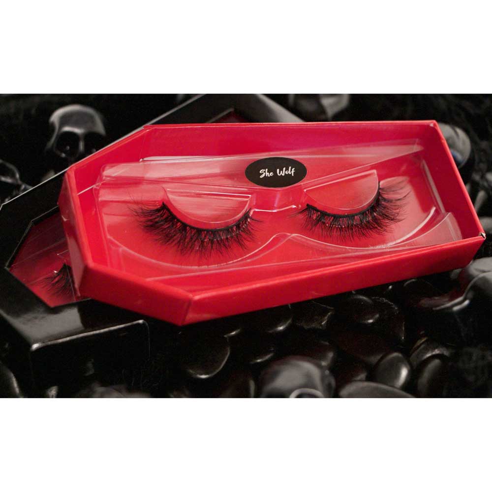 Red false eyelash packaging with lashes on a black stone surface