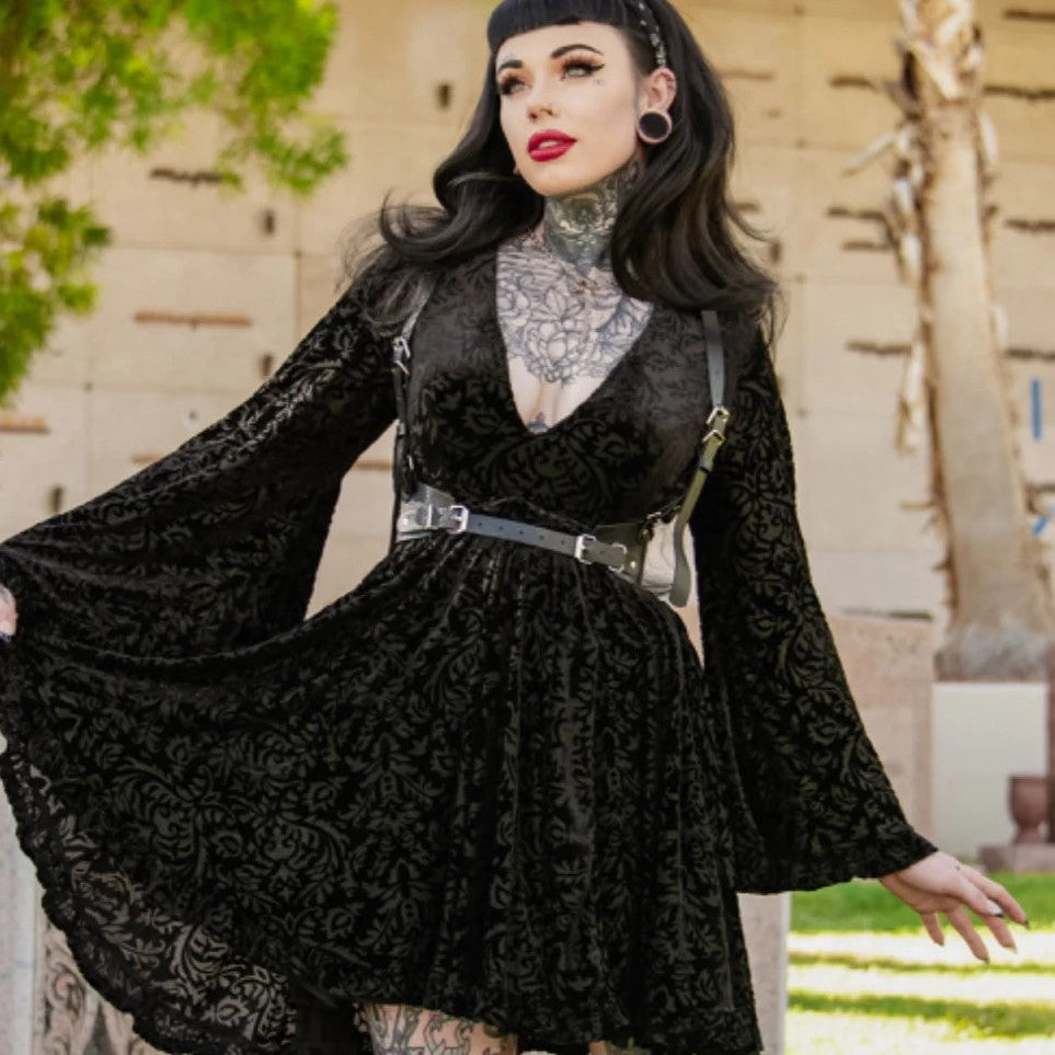 Woman wearing a black lace dress with long sleeves in an outdoor setting.
