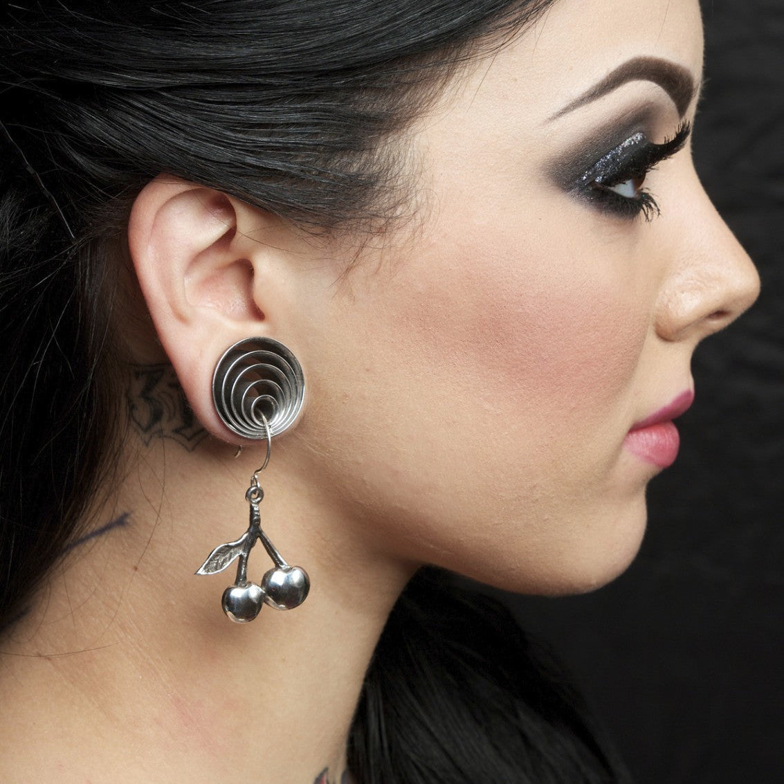 Close-up of a woman wearing a unique earring with a dark background