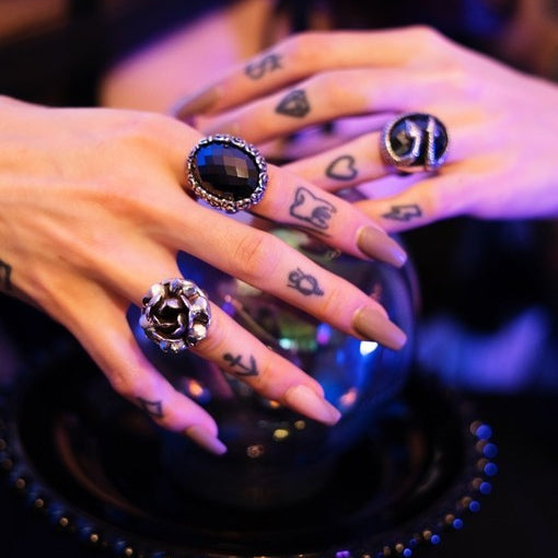 Close-up of hands with black gemstone rings on a dark background