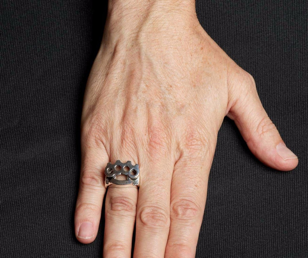 Hand wearing a silver ring with a black background