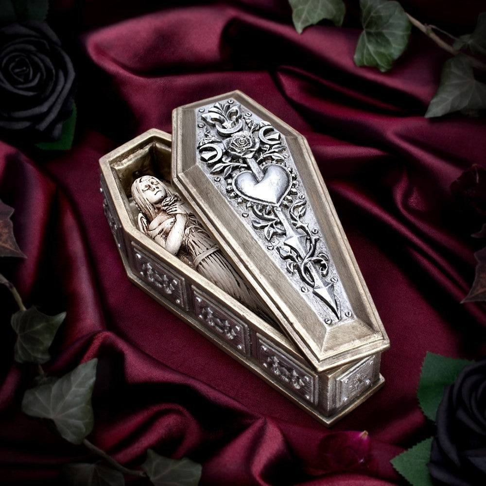 Decorative coffin box with intricate designs on a dark fabric background