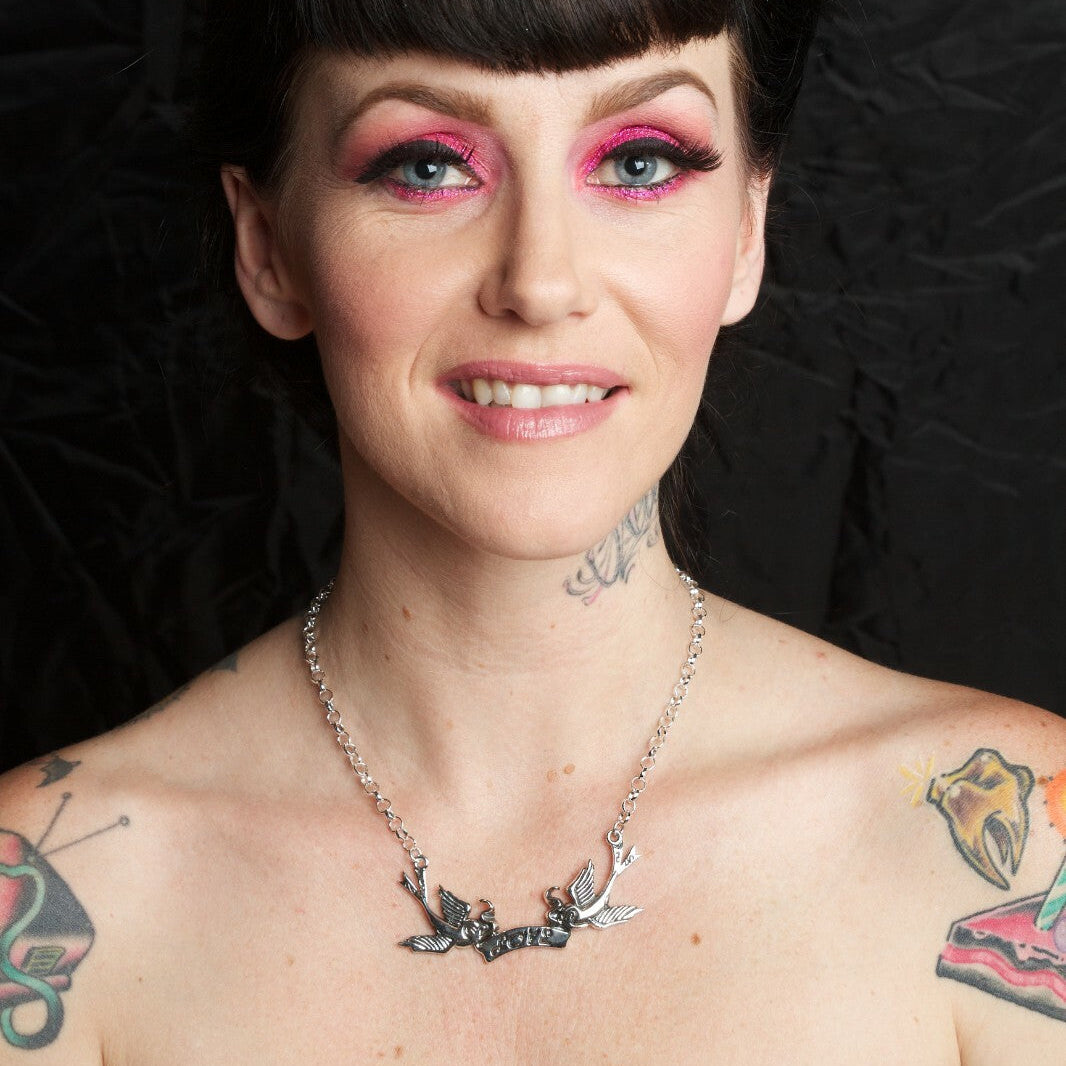 Woman with tattoos and piercings wearing a black strapless top against a dark background