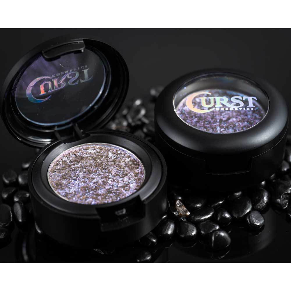 Makeup compact with glittery powder and 'Curst' branding on a dark background