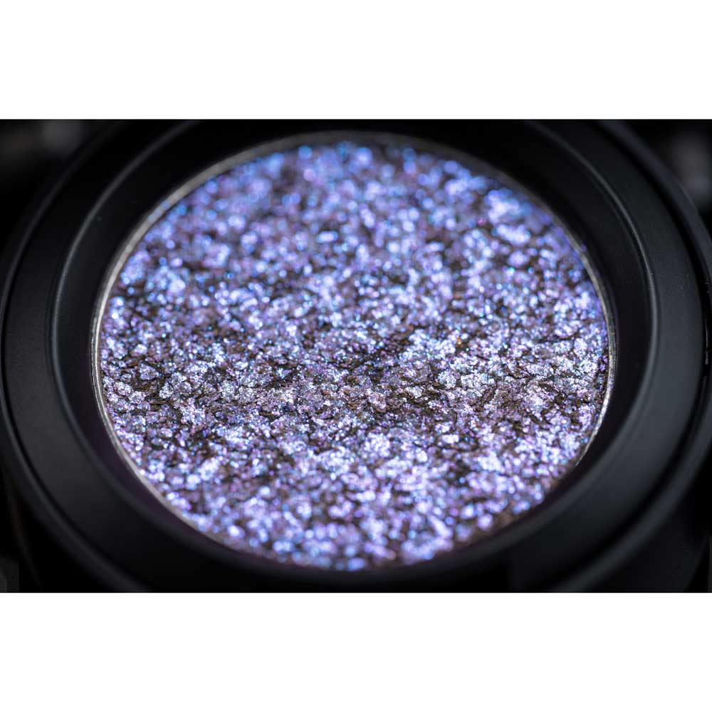 Close-up of a purple glittery eyeshadow in a compact