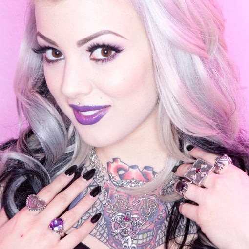 Person with pastel hair and colorful makeup against a pink background